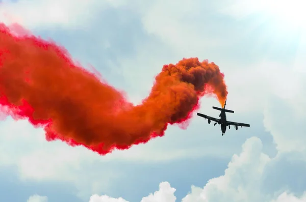 Avión vuela en zigzags con un humo rojo rastro en el cielo — Foto de Stock