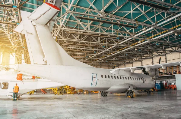 Airliner aircraft turboprop in a hangar with an open gate to the service. — Stock Photo, Image