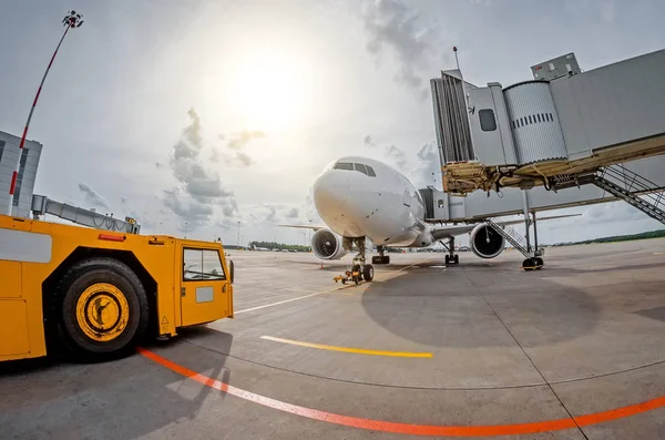 Aparcamiento en el aeropuerto un avión en la teletrampa y un tractor de aeródromo, listo para la salida al vuelo — Foto de Stock