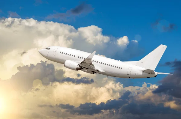Επιβατών λευκό αεροπλάνο απογειώνεται με φόντο cumulus σύννεφα στο ηλιοβασίλεμα — Φωτογραφία Αρχείου