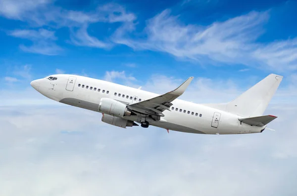 Passenger airplane flies on a flight level against a background of clouds and a blue sky Stock Photo