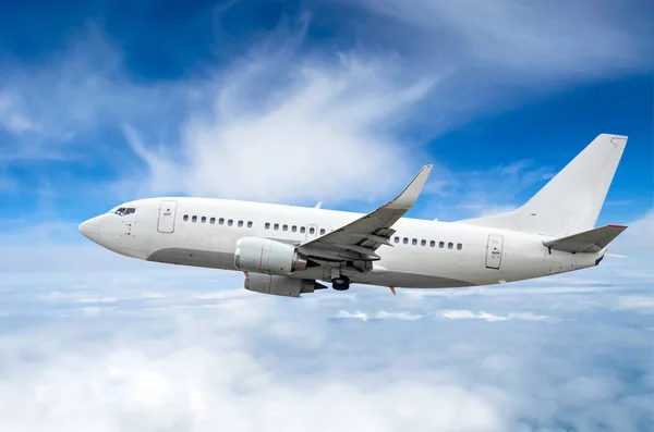 Avión de pasajeros vuela en un nivel de vuelo sobre un fondo de nubes y un cielo azul — Foto de Stock