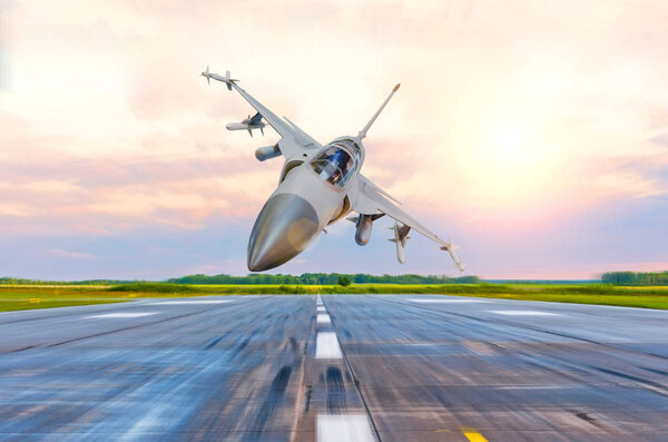 Military fighter jet flies at high speed over the taxiway at the airport.