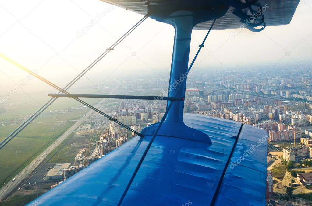 View in the porthole airplane of a turboprop aircraft biplane on the city streets and houses.