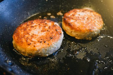 İki yuvarlak pirzola et Dana gelen bir kızartma tavası ve petrol yanmış.