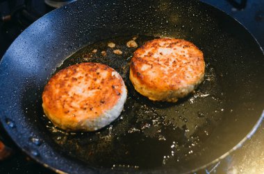 İki yuvarlak pirzola et Dana gelen bir kızartma tavası ve petrol yanmış.