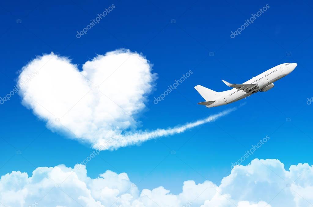 Airplane in the blue sky with clouds, left a trace in the form of a cloud of the heart.