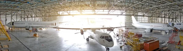 Tres aviones de pasajeros en un hangar con una puerta abierta para el servicio, vista del panorama . —  Fotos de Stock