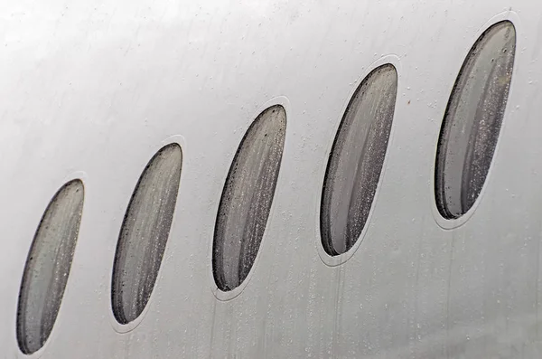 Ventanas de ojo de buey de un avión tiempo húmedo en gotas de lluvia de agua, primer plano . — Foto de Stock