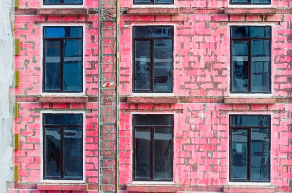 Janelas de uma casa em construção de blocos de cinzas pintados de vermelho . — Fotografia de Stock