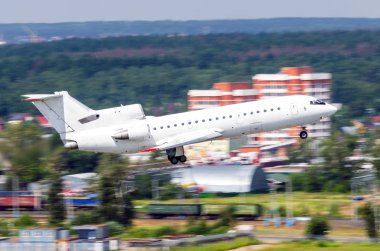 Beyaz uçak kalkış şehir ve orman sanayi bölgesinin arka planı.