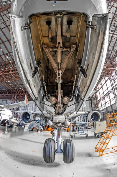 Large passenger aircraft on service in an aviation hangar rear view of front landing gear. — Stock Photo, Image