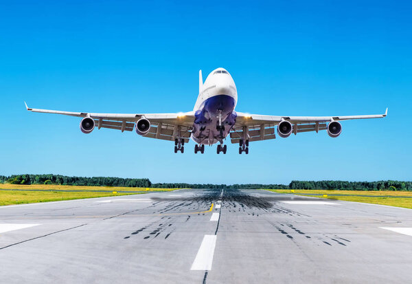 Пассажирский самолет приземляется на голубом небе на взлетно-посадочной полосе
.