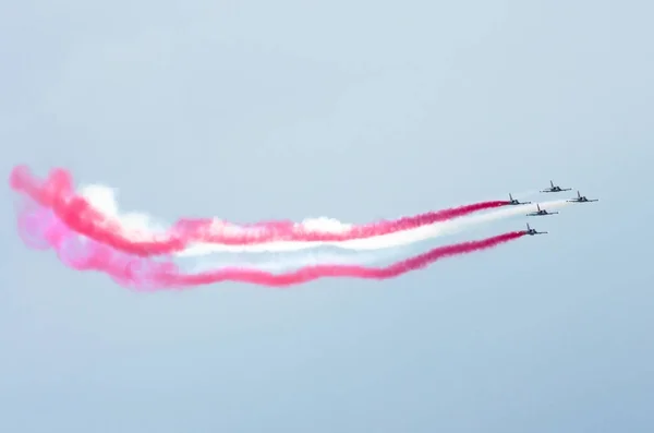 Un groupe d'avions de chasse vole avec une traînée de fumée rouge blanc . — Photo