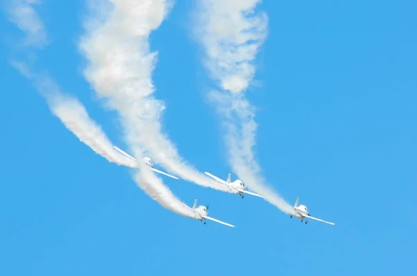 Avión de motor ligero con un rastro de humo blanco vuela en grupos en el cielo azul con luz solar y deslumbramiento . — Foto de Stock
