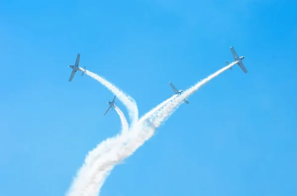 Літак легкого двигуна зі слідом білого диму літає групами на блакитному небі з сонячним світлом і відблисками . — стокове фото
