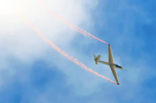 Avión planeador volando alto en el cielo con un rastro de humo rojo . — Foto de Stock