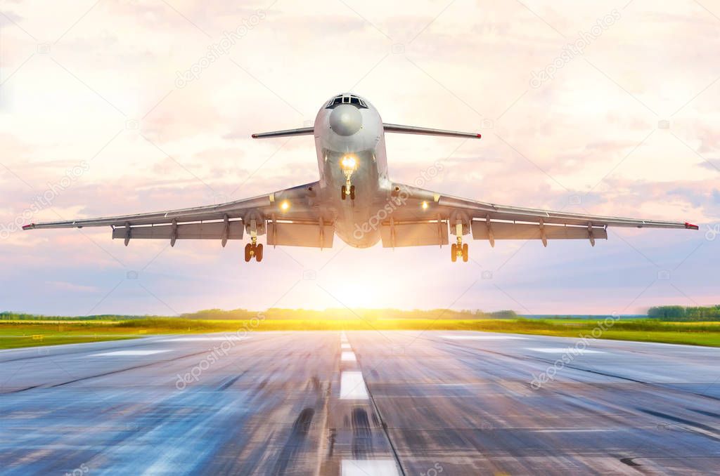 Passenger airplane landing at sunset on a runway.