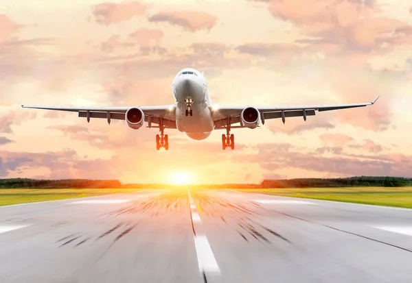 Avión de pasajeros aterrizando al atardecer en una pista . —  Fotos de Stock