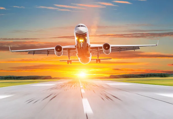 Avión de pasajeros aterrizando al atardecer en una pista . — Foto de Stock