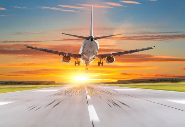 Avión de pasajeros aterrizando al atardecer en una pista . — Foto de Stock