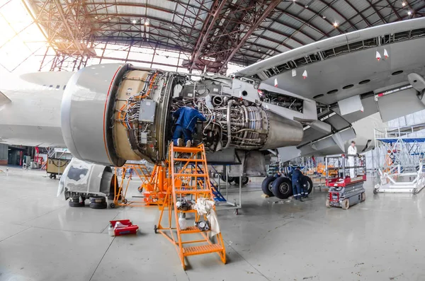 Specialist mechanic repairs the maintenance of a large engine of a passenger aircraft in a hangar. — Stock Photo, Image