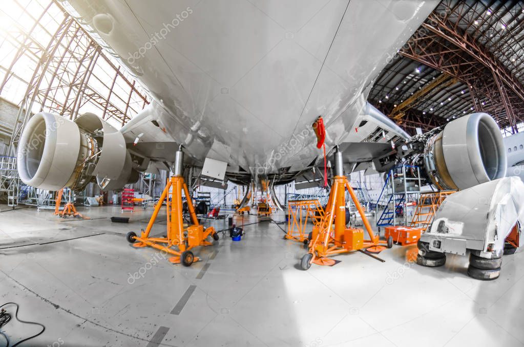 A large aircraft for service maintenance on special jacks in the hangar.
