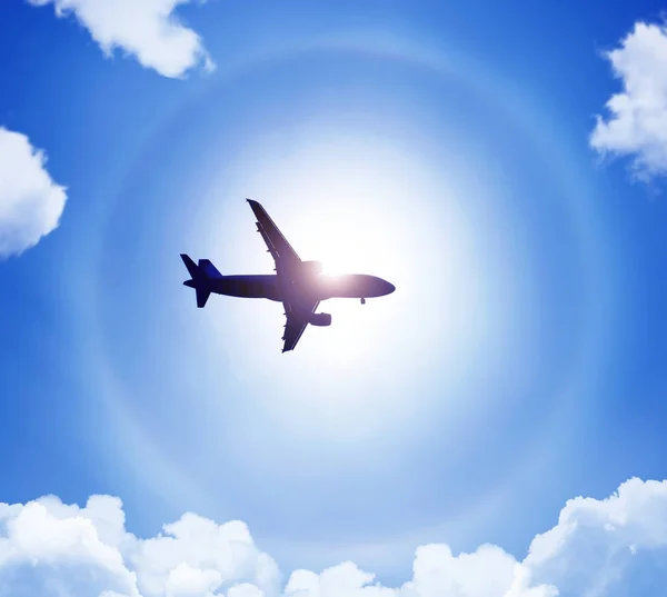 Silueta de un avión en el cielo sol y halo en las nubes . — Foto de Stock