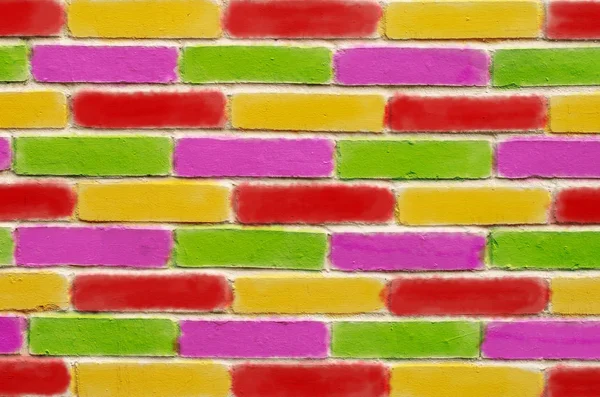 Mur z cegły, zielony fioletowy czerwony i żółty klocki malowane. — Zdjęcie stockowe