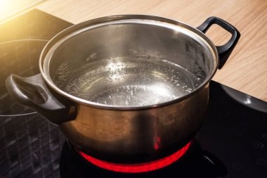 Kaynar su indüksiyon Ocak kırmızı sıcak plaka üzerinde metal tava.