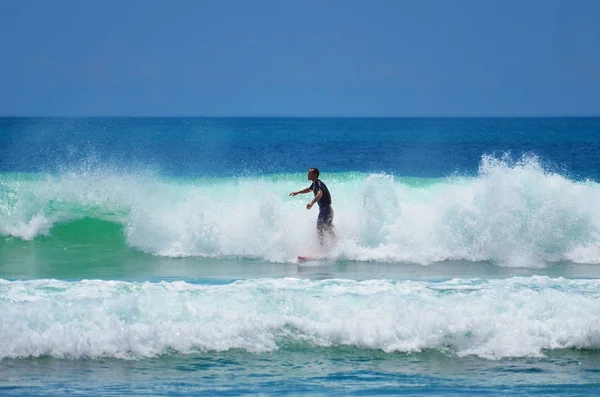 De surfer in groen blauw van de oceaan Golf, surfen. Indonesië, Bali, 10 November 2011. — Stockfoto