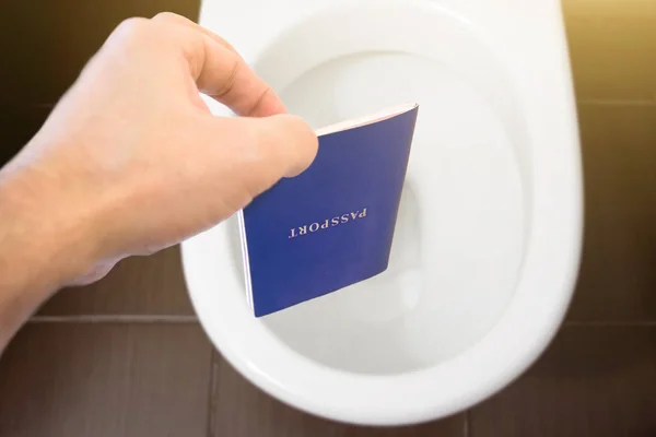 Hand hält den Reisepass des Bürgers über die Toilette, wirft seinen Reisepass hinaus. Konzept - Wechsel der Staatsbürgerschaft, Verlust des Passes, politische Probleme, Verletzung von Rechten. — Stockfoto