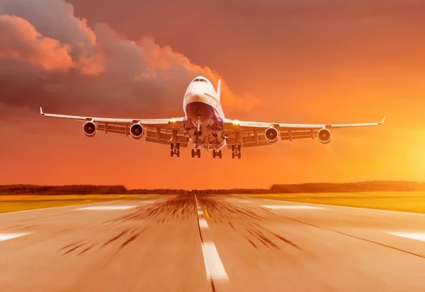 Avião de passageiros a aterrar ao pôr-do-sol numa pista . — Fotografia de Stock
