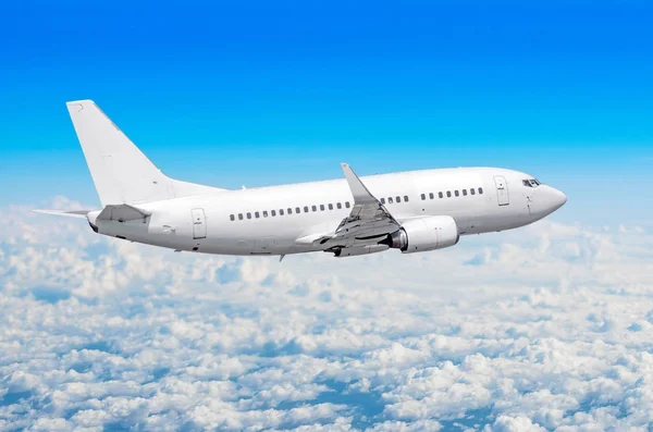 Passenger plane flies on a train above clouds and blue sky. Stock Photo