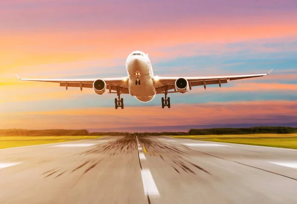 Avión de pasajeros aterrizando al atardecer en una pista . — Foto de Stock