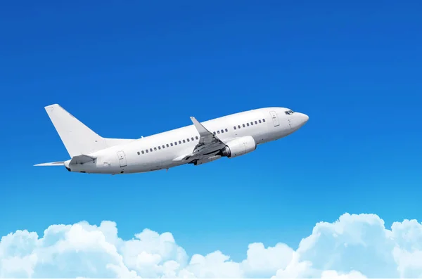 Επιβατικό αεροπλάνο που πετούν σε ένα τρένο πάνω από τα σύννεφα και το γαλάζιο του ουρανού. — Φωτογραφία Αρχείου