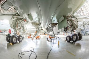 Hangarda tekerleklerin şasi raflar arasında uçak altından göster.