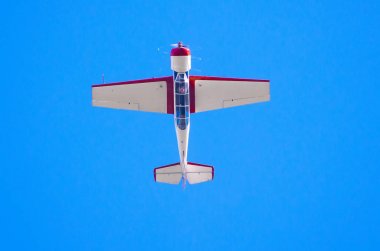 Airplane flys upside down in the blue sky. clipart