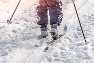 Kışın buz gibi bir günde parkta kayak yapan bir adam. Ayakları ve botları yakından görüyor..