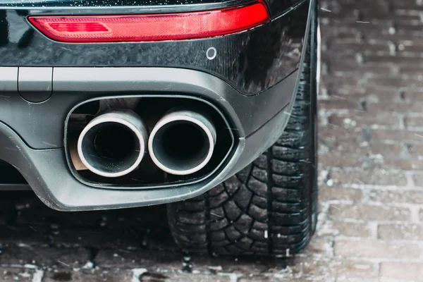 Close-up de um carro luzes de estacionamento tubo de escape dupla, luzes de freio e pneus de roda . — Fotografia de Stock