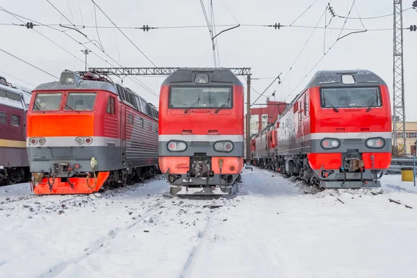 Três locomotivas elétricas vermelhas estão alinhadas na ferrovia no depósito de neve de inverno . — Fotografia de Stock