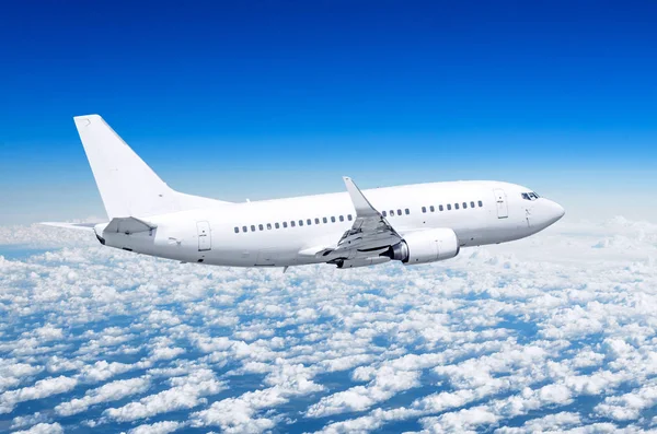 Passenger airplane fly on a hight above clouds and blue sky. Stock Image