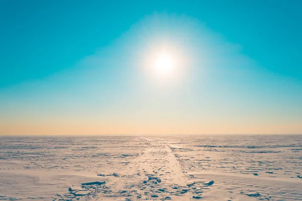 Road w śniegu w zimowych śnieżna pustynia w turquoise niebo jasne słońce świeci. — Zdjęcie stockowe