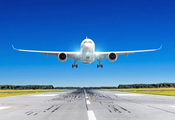 Avión de pasajeros con luces de aterrizaje brillantes aterrizando en buen tiempo claro con un cielo azul en una pista . —  Fotos de Stock