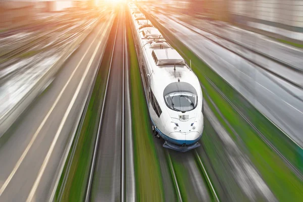 O trem de passageiros de alta velocidade viaja na grama verde da ferrovia de alta velocidade. Vista superior com efeito de movimento, fundo lubrificado . — Fotografia de Stock