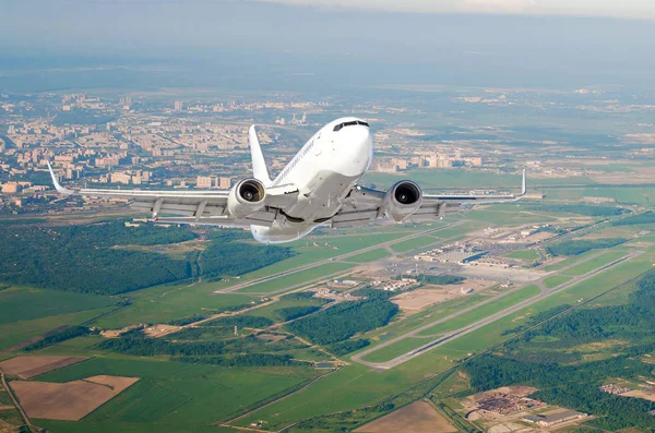 Airplane is climb flight level high view in the air, against the background of the airport of the runway, city, fields, forests and roads.