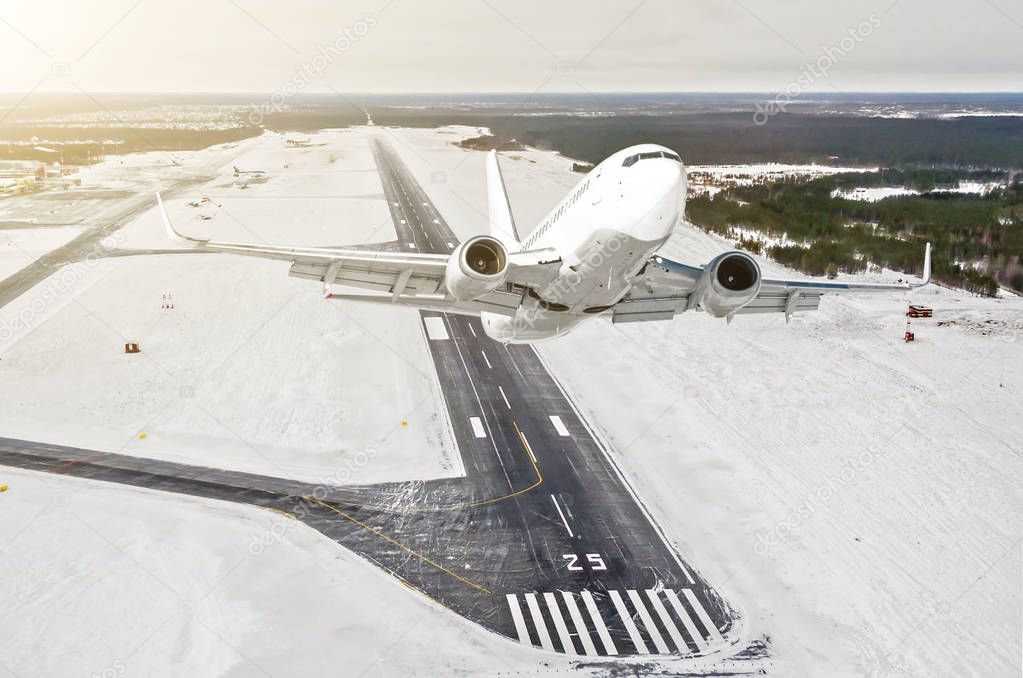 Airplane is climb flight level high view in the air, against the background of the winter airport of the runway, city, snow, forests and roads.