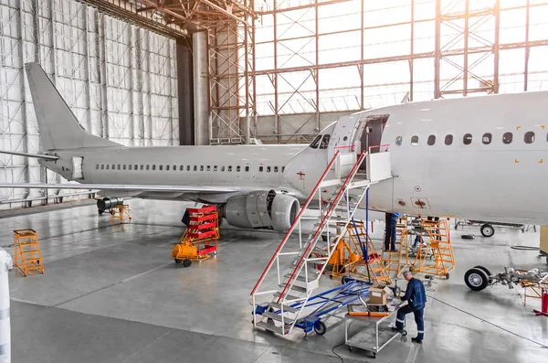 Aircraft during repair, technical inspection is a working technician. View of nose, a cockpit with a staircase leading into the entrance. In background, the other tail and fuselage of the airplane. — Stock Photo, Image