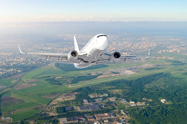 Airplane is climb flight level high view in the air, against the background sky horizon the airport of the runway, city, fields, forests and roads.