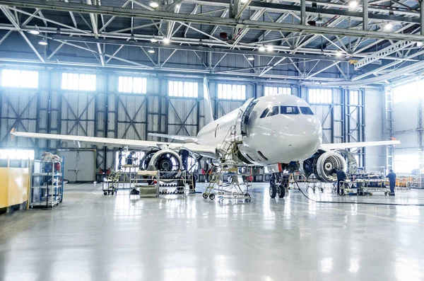 Utasszállító repülőgép motor és a törzs ellenőrzése javítás a repülőtéri hangár karbantartás. — Stock Fotó